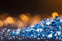 Sparkling blue crystal fragments with golden bokeh lights in background create luxurious abstract composition for jewelry and luxury product marketing.