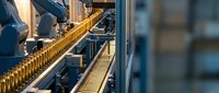 Automated production line with robotic arm handling glass bottles in modern manufacturing facility with industrial conveyor system and quality control.