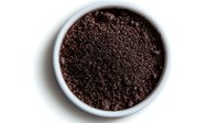Fresh ground coffee in white ceramic bowl viewed from above, dark roasted arabica coffee grounds with rich texture and aroma for brewing and barista use.