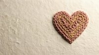 Handmade wicker heart decoration on textured beige background for romantic crafts and Valentine's Day projects.