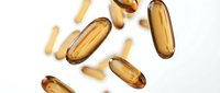 Golden vitamin capsules floating on white background for health and wellness supplement marketing materials.