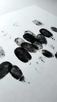 Fingerprints and footprints on white paper surface, forensic evidence collection for criminal investigation, law enforcement, and identification purposes.