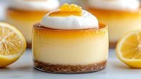 Creamy lemon cheesecake dessert topped with whipped cream and lemon curd on graham cracker crust, served in individual glass portion with fresh citrus garnish.