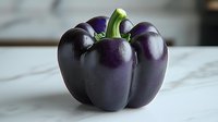 Fresh purple bell pepper with glossy skin and green stem on white marble surface, dramatic lighting highlights natural texture and vibrant color.