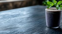 Dark purple smoothie with fresh mint garnish in glass on textured slate surface, moody lighting creates dramatic atmosphere for food photography.