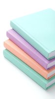 Stack of pastel hardcover notebooks in mint, lavender, and peach tones isolated on white background, perfect for stationery and education concepts.