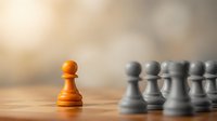 Golden pawn standing alone facing row of gray pawns on wooden board, representing leadership, uniqueness, courage, and standing out from the crowd.