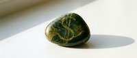 Smooth dark green stone with golden yellow vein patterns isolated on white background, suitable for design, wellness, and nature-themed projects.