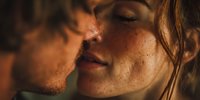 Intimate close-up of young couple sharing tender moment with warm golden lighting, romantic connection between man and woman with freckled skin.