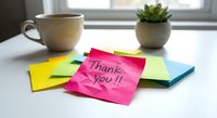 Colorful sticky notes with thank you message on white desk beside coffee cup and succulent plant creating workspace gratitude concept for office motivation.
