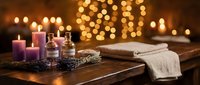 Relaxing spa setup with aromatic candles, essential oils and towels creating peaceful wellness atmosphere for massage therapy and self-care rituals.