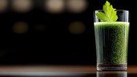 Fresh green smoothie with celery garnish in tall glass on dark background with copy space, healthy detox drink for wellness and diet programs.