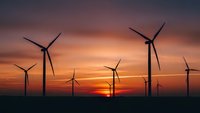 Wind turbines silhouetted against dramatic sunset sky generating renewable energy for sustainable power production and environmental conservation.