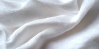Close-up of soft white fabric with gentle waves and folds, showcasing texture and light play. Suitable for backgrounds, textile design, and wellness content.