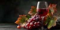 Red wine glass with fresh grape cluster and autumn vine leaves on dark wooden table creating elegant seasonal atmosphere for wine tasting events.