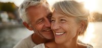 Happy senior couple embracing outdoors at sunset, mature man and woman smiling together in golden hour light for retirement lifestyle content.