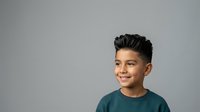 Young boy with dark hair and olive complexion wearing teal t-shirt, smiling at camera against neutral gray background, suitable for youth, family, and lifestyle design projects.