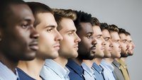 Diverse group of professional men in business attire standing in profile line formation representing teamwork, leadership and corporate unity concepts.