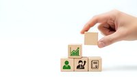 Hand placing wooden cube blocks with business icons showing growth chart, person and presentation symbols for corporate strategy concept.