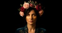 Young woman with floral crown of roses in dark romantic portrait against black background for fashion and beauty concepts.