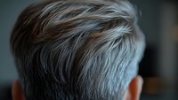 Close-up of silver gray hair on mature person showing natural aging process, textured strands against dark background for health and beauty concepts.
