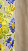 Colorful floral embroidery with blue and yellow flowers on natural linen fabric showcasing traditional needlework craftsmanship for textile and fashion projects.