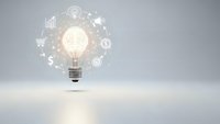 Glowing light bulb with business icons and symbols floating around representing innovation, creativity, and entrepreneurial ideas on clean background.