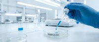 Medical researcher in blue gloves using pipette to analyze liquid sample in sterile laboratory environment for scientific testing and analysis.