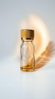 Small glass bottle with golden cap and dried pampas grass shadow on white background for cosmetic and aromatherapy product photography.