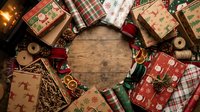 Festive Christmas gift boxes wrapped in colorful holiday paper arranged in a circle on a rustic wooden table with pine cones and ribbons.