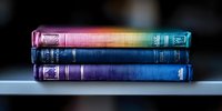Stack of vintage books with colorful rainbow gradient spines arranged horizontally on shelf, creating artistic composition against dark background.