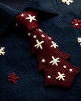 Navy blue knitted sweater with burgundy necktie featuring white snowflake pattern. Festive winter holiday fashion accessories for seasonal celebrations.