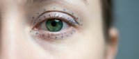 Close-up of green eye with natural freckles around orbital area showing detailed iris patterns and skin texture for beauty and skincare concepts.