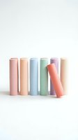 Colorful cylindrical cosmetic containers in pastel pink, peach, blue, green, lavender and cream arranged in a row with one tilted tube for product packaging and branding.