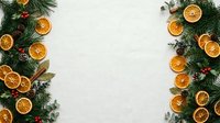 Dried orange slices and evergreen branches with red berries arranged on white background, ideal for holiday and seasonal design projects.