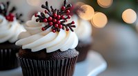 Chocolate cupcake with swirled white frosting topped with red berry and pine cone decoration against blurred holiday lights background, festive winter dessert.