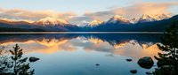 Serene mountain lake at sunrise with snow-capped peaks reflecting in calm water, peaceful alpine landscape with golden light and mirror-like surface.