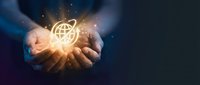 Businessman hands holding glowing globe network icon with sparkling light effects on dark background representing global connectivity and digital transformation.