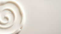 Creamy white swirl texture with smooth flowing curves on neutral background for skincare cosmetics and beauty product design applications.