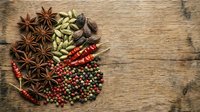 Aromatic spices and herbs arranged on rustic wooden background with copy space for culinary designs and cooking projects.