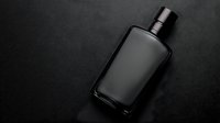 Dark glass bottle on black textured background with dramatic lighting and reflective surface, luxury cosmetic or fragrance packaging mockup for premium product design.