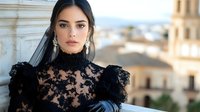 Young woman in luxurious black lace dress with high neck and puff sleeves poses against blurred architectural background, wearing elegant earrings and dark veil.