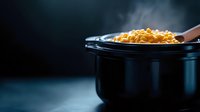 Steaming hot macaroni and cheese in black pot with wooden spoon on dark background. Comfort food cooking concept for restaurant menus and recipes.
