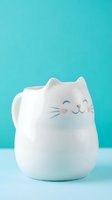 Adorable white ceramic cat mug with smiling face and whiskers on turquoise background for kitchen decor and beverage enjoyment.