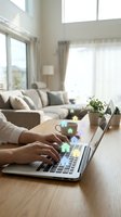 Person using laptop for smart home automation with digital house icons floating above keyboard in modern bright living room interior.