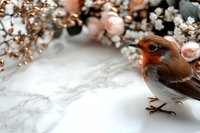 European robin perched on marble surface with soft pink roses and dried flowers creating romantic spring composition. Gentle nature photography.