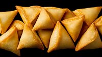 Golden crispy samosas arranged in row on black background, traditional Indian fried pastry snacks ready for serving at restaurant or food delivery.