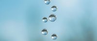 Transparent water droplets floating against a soft blue background, reflecting light with a clean, fresh aesthetic for nature and wellness projects.