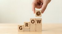 Hand placing wooden cube with growth chart icon completing GROW word concept for business development and success strategy on wooden surface.