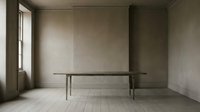 Minimalist interior with long wooden table in empty room with natural light from window, neutral beige walls and white tile flooring.